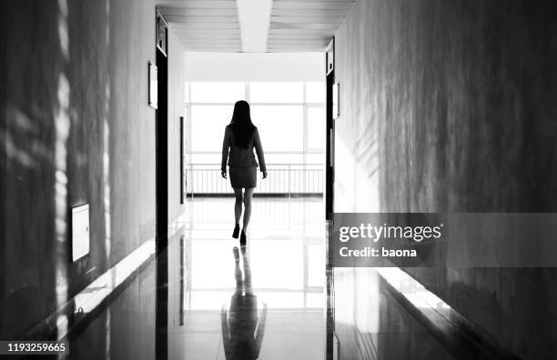 businesswoman through the office corridor - woman walking out door silhouette stock pictures, royalty-free photos & images
