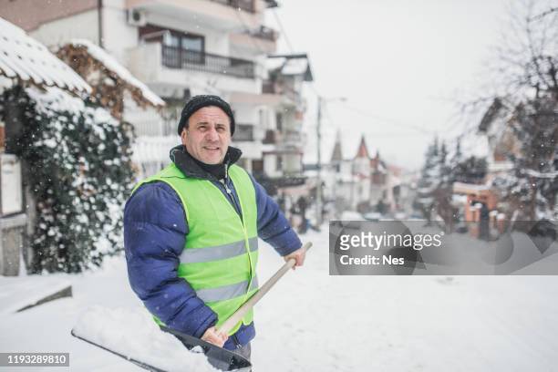 äldre man rensa snö på gatan - city of spades bildbanksfoton och bilder