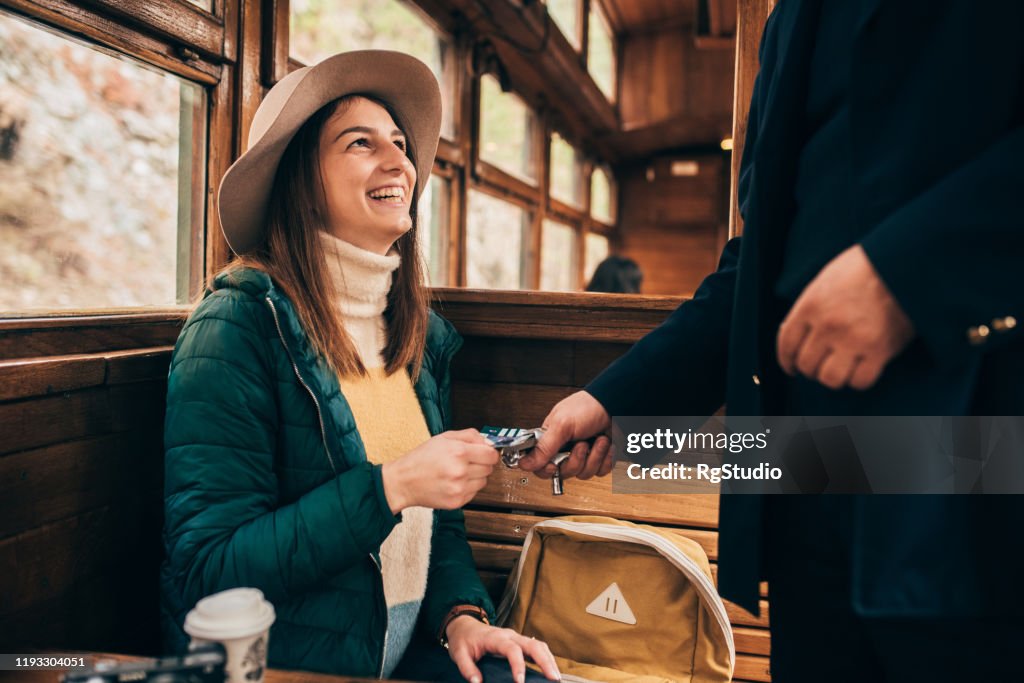 Female passenger showing the ticket to the train conductor