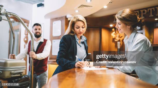 businesswoman register in hotel bellhop moving luggage on cart for hotel guest - star hotel stock pictures, royalty-free photos & images