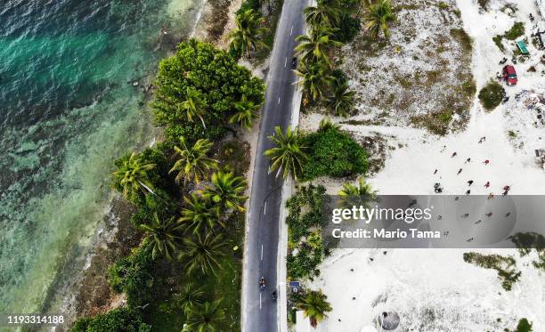 An aerial view shows community members playing volleyball on an area of reclaimed land, a countermeasure to the rising sea, next to the lagoon on...