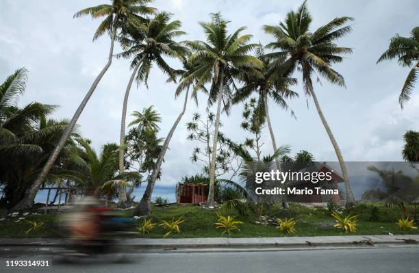 Scooter passes graves located near the Pacific Ocean on November 23, 2019 in Funafuti, Tuvalu. The low-lying South Pacific island nation of about...