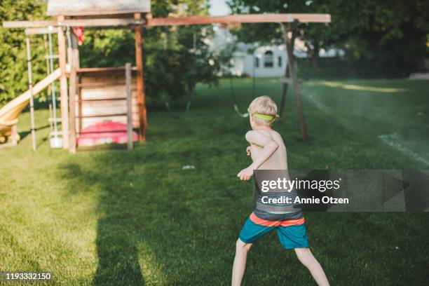 playful boy running against lawn - spielplatz einrichtung stock-fotos und bilder