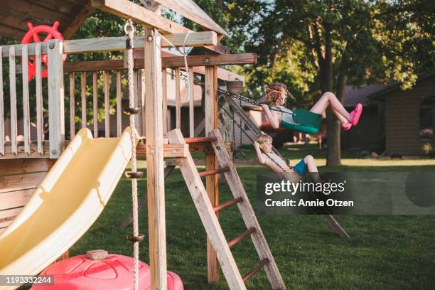 kids swinging on backyard swing set - family garden play area stock pictures, royalty-free photos & images