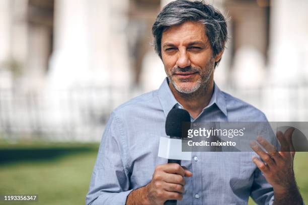 reporter holding microphone on the street - newscaster stock pictures, royalty-free photos & images