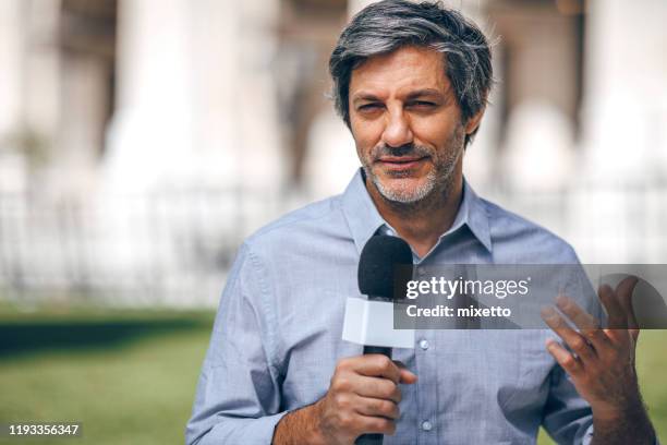 reporter holding microphone on the street - tv journalists stock pictures, royalty-free photos & images