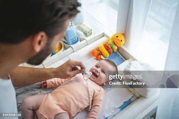 nettes fröhliches baby und ihr vater in einem kinderzimmer - baby changing mat stock-fotos und bilder