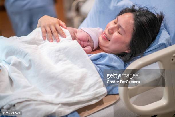 asian mother having skin-to-skin time in the delivery room stock photo - showus doctor stock pictures, royalty-free photos & images