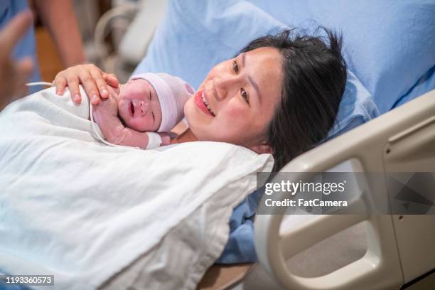 madre asiática teniendo tiempo piel a piel en la foto de stock de la sala de parto - hospital gown fotografías e imágenes de stock