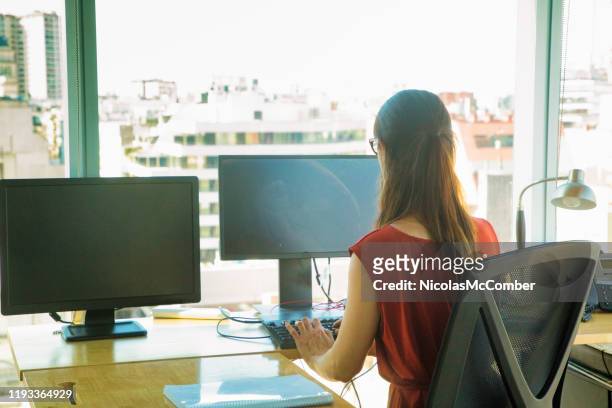rear view of female office worker typing as her computer goes blank from power outage - dual stock pictures, royalty-free photos & images