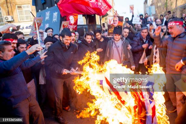 Protesters chant slogans and hold up posters of Gen. Qassem Soleimani while burning representations of British and Israeli flags, during a...