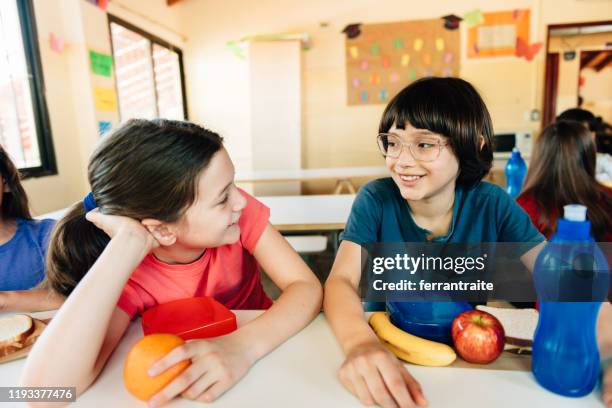 studenti delle elementari a pranzo a scuola caffetteria - girls laughing eating sandwich foto e immagini stock