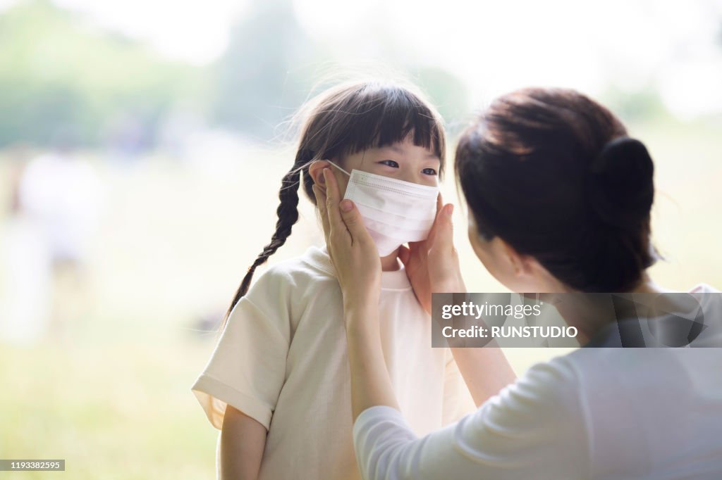 Mother putting on pollution mask to girl