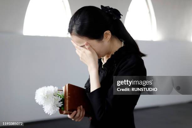 bereaved crying at funeral - viuda fotografías e imágenes de stock