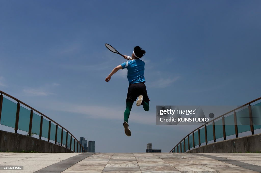 Young man swinging tennis racket