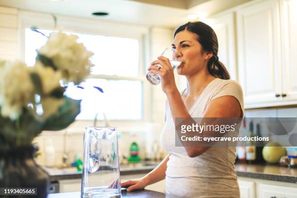 beautiful young adult millennial female using water in residential home - water stock pictures, royalty-free photos & images