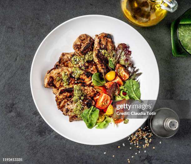 grilled pork cutlets with salad in a bowl on black background - vleesgerecht stockfoto's en -beelden