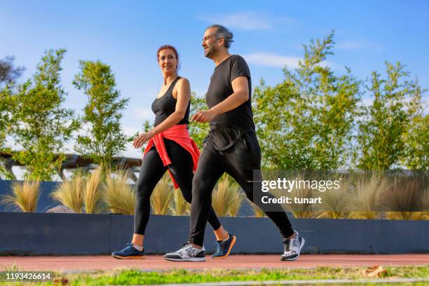 mature adult couple walking in a park - walking imagens e fotografias de stock