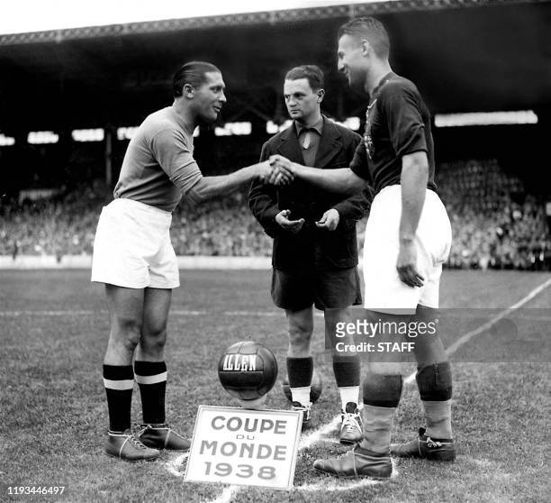 French referee Georges Capdeville looks on as the captains of the Italian and Hungarian national soccer teams Giuseppe Meazza and Gyorgy Sarosi shake...