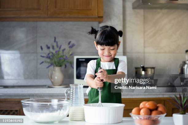 child girl enjoy cooking in the kitchen. happy asian kid is preparing the dough, bake cookies in the kitchen. - kids cooking stock pictures, royalty-free photos & images