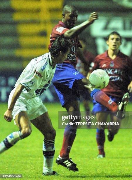 Mario Acevedo of the Municipal of Guatemala intends to kick the ball 14 September 2001, and Alvaro Jimenez of Guatemala watches from behind during...