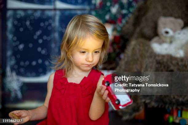 beautiful toddler girl, opening presents on christmas night - tiny beautiful things opening night celebration stock pictures, royalty-free photos & images