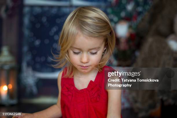 beautiful toddler girl, opening presents on christmas night - tiny beautiful things opening night celebration stock pictures, royalty-free photos & images