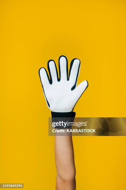 hand of little boy with soccer goalkeeper gloves on yellow background - gants de sport photos et images de collection