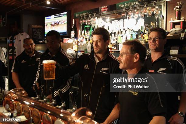 Cory Jane of the All Blacks delivers a pint for a punter at the Mornington Tavern watched by John Afoa and Sitiveni Sivivatu on July 19, 2011 in...