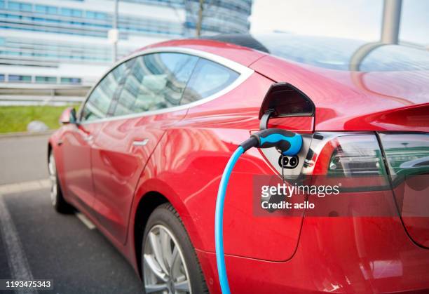 red tesla model s electric car connected to a recharging station - red car wire stock pictures, royalty-free photos & images