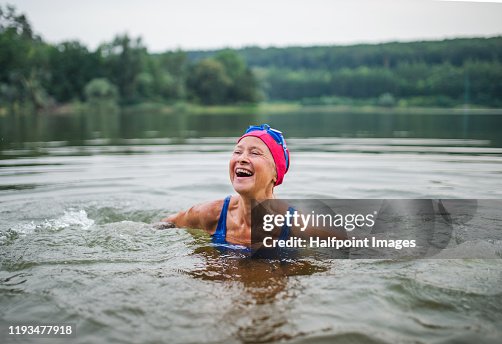 Active senior woman standing in lake outdoors in nature, laughing. Active senior woman standing in lake outdoors in nature, laughing.