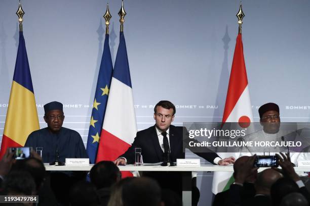 French President Emmanuel Macron flanked by Niger's President Mahamadou Issoufou and Chad's President Idriss Deby speaks during a press conference as...