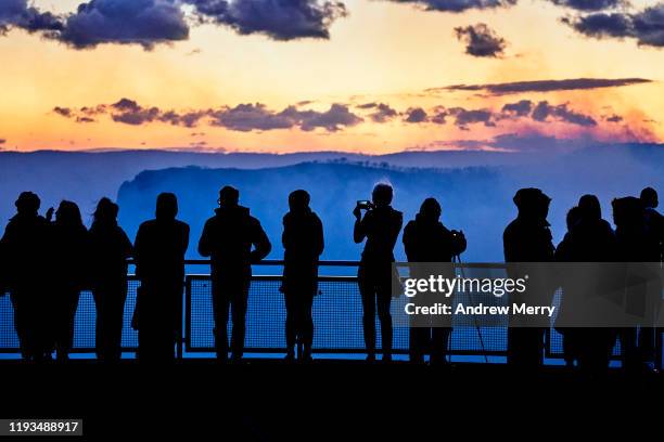 silhouette of group of tourists on viewing platform looking at bushfires in blue smoke filled valley at dusk, blue mountains, australia - blue mountains fire stock pictures, royalty-free photos & images