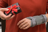 Woman With Gift box and Contused Hand In Stabilizer