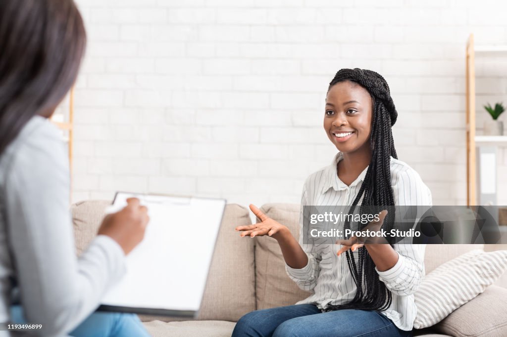 Happy black woman talking to psychologist after successful therapy session