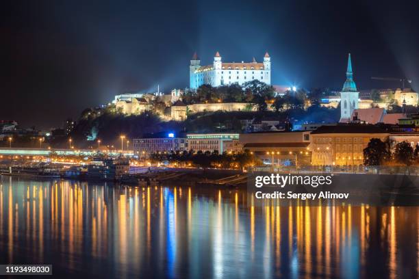 illuminated bratislava castle with reflection in danube river at night - slovakia castle stock pictures, royalty-free photos & images