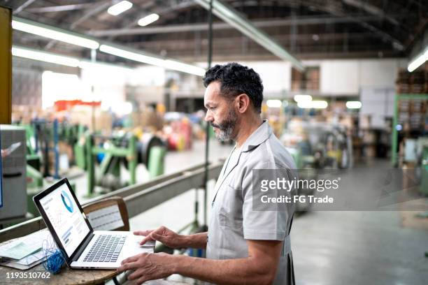 techniker mit laptop während der arbeit in einer fabrik - factory stock-fotos und bilder