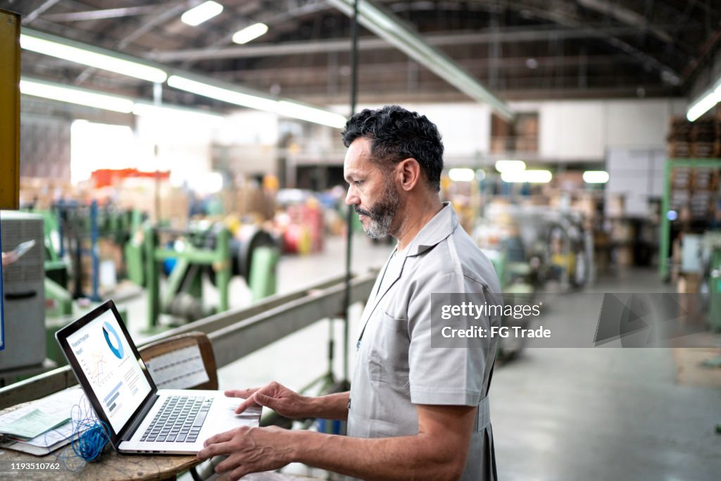 Tecnico che utilizza un laptop mentre lavora in fabbrica