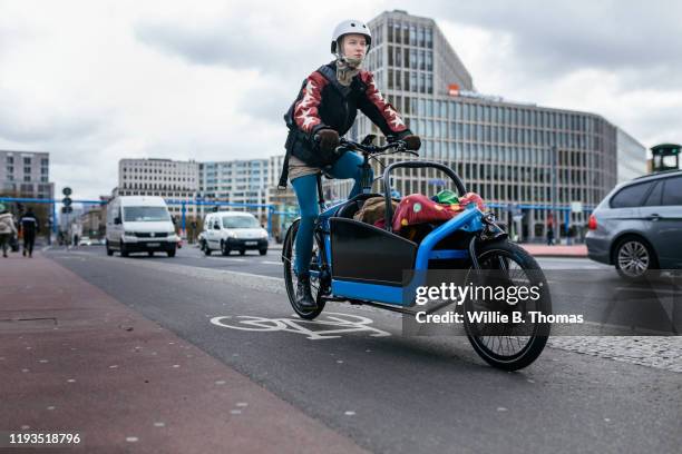 single mother riding cargo bike carrying child - protective sportswear stock pictures, royalty-free photos & images