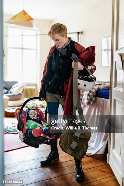 single mother with baby in carrier ready to go out on bicycle - baby bag stock-fotos und bilder