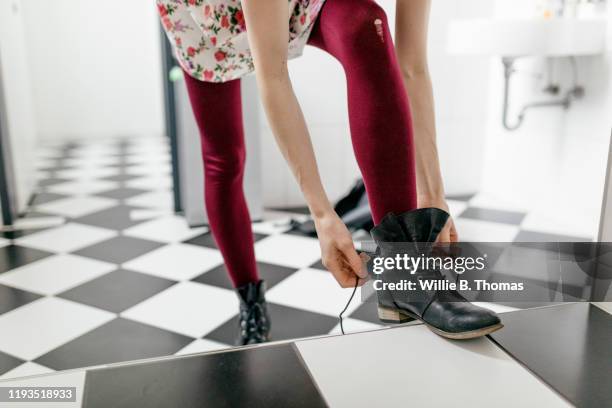 woman putting on boots in bathroom - stiefel stock-fotos und bilder