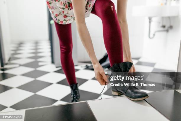 woman putting on boots in bathroom - woman boots fotografías e imágenes de stock