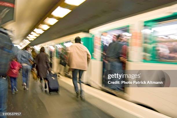 subway's users walking on platform of paris metro during rush hour. photo shot in slow shutter speed (long exposure). - subway paris stock-fotos und bilder