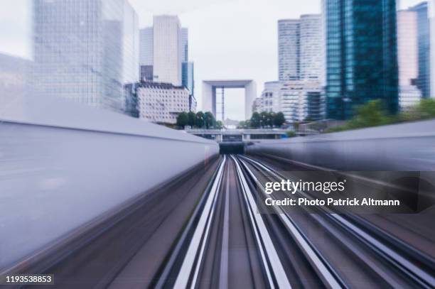 paris metro's (subway, underground) train in motion about to reach the tunnel under financial center district, shot from conductor cabin in long exposure (slow shutter speed). - grande arche stock pictures, royalty-free photos & images