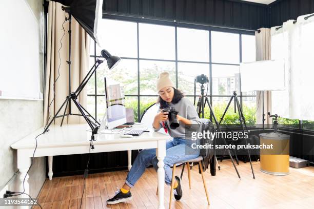 side view of female freelancer photographer checking photos on a digital camera . - freelance work stock pictures, royalty-free photos & images