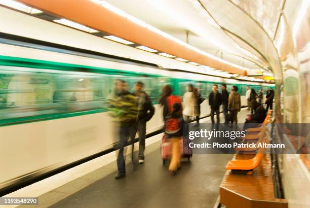 subway's users arriving or waiting for next train on curved platform of paris metro during the day. photo shot in slow shutter speed (long exposure). - long exposure train stock pictures, royalty-free photos & images