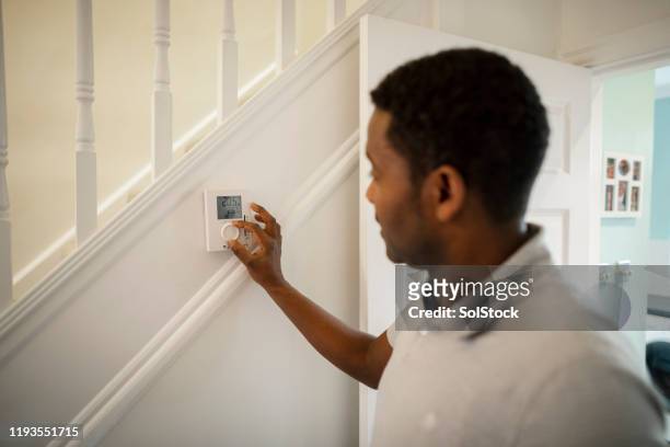 turning thermostat down - energy efficient fotografías e imágenes de stock
