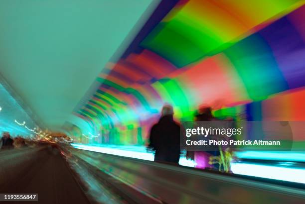 subway's users are riding on moving walkway in long underground tunnel in paris metro's station off peak hours. shot in slow shutter speed (long exposure). - fast shutter speed stock-fotos und bilder