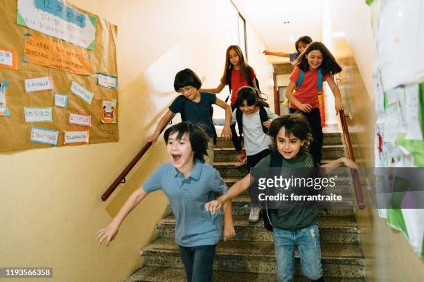 elementary age students running in school corridors on the last day of school - last day of school stock pictures, royalty-free photos & images
