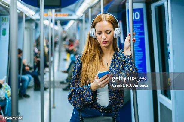 woman with smartphone and headphones traveling in the subway - train vehicle imagens e fotografias de stock